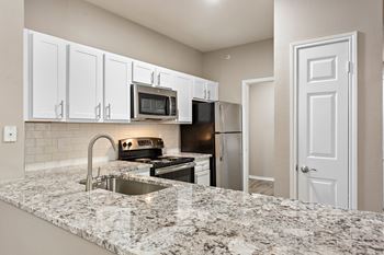 A kitchen with granite countertops and stainless steel appliances